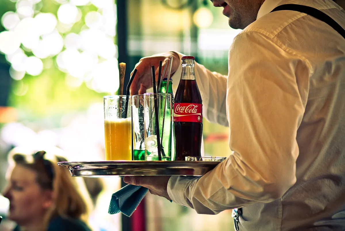 Camarero sirviendo bebidas en una bandeja en un restaurante